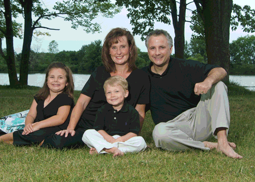 In this portrait, the girl's head was replaced with her head from an image created two photos later. Mom's expression was from the very next image. Mom and dad had shiny areas of their faces toned down and dark areas under their eyes lightened. Stray hair on mom's head was eliminated as was a dead limb on the tree on the left.